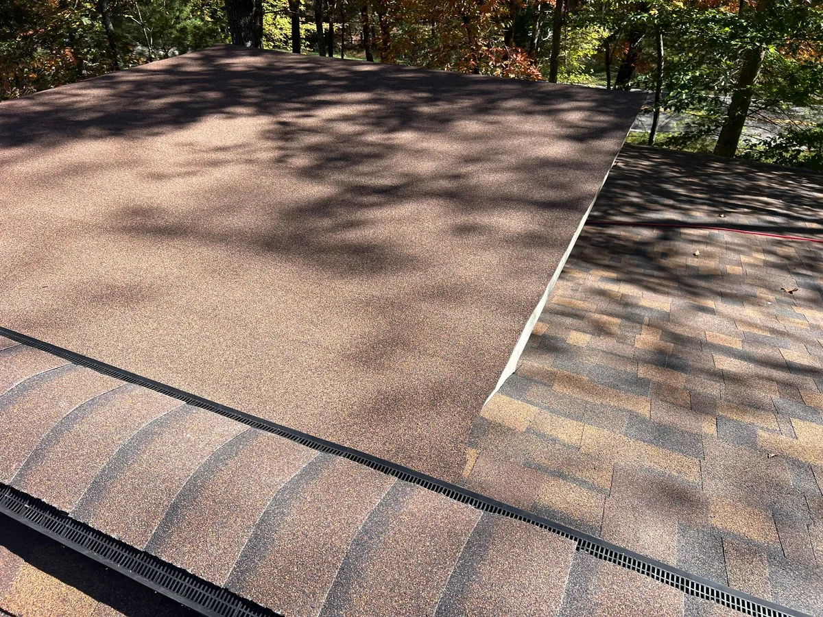 Low-slope plane meeting the steeper roof, with two separate ridge-vent runs capped in matching shingle