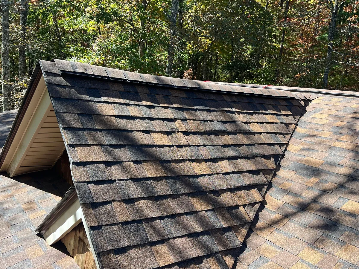 Dormer gable in warm brown architectural shingles with its own ridge vent, valley running down into the main roof