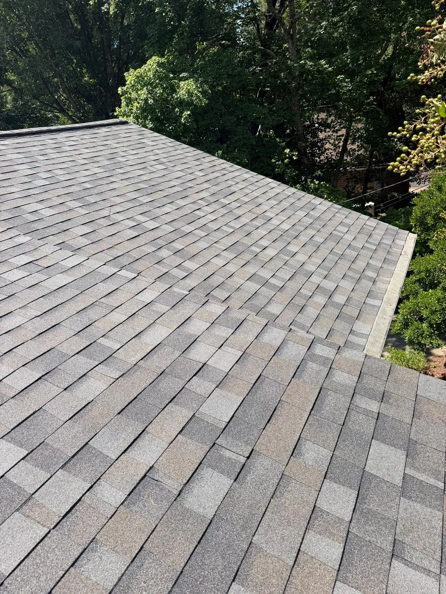 Shingle slope dropping to meet a lower hip, with a freshly cut rake edge along the gable