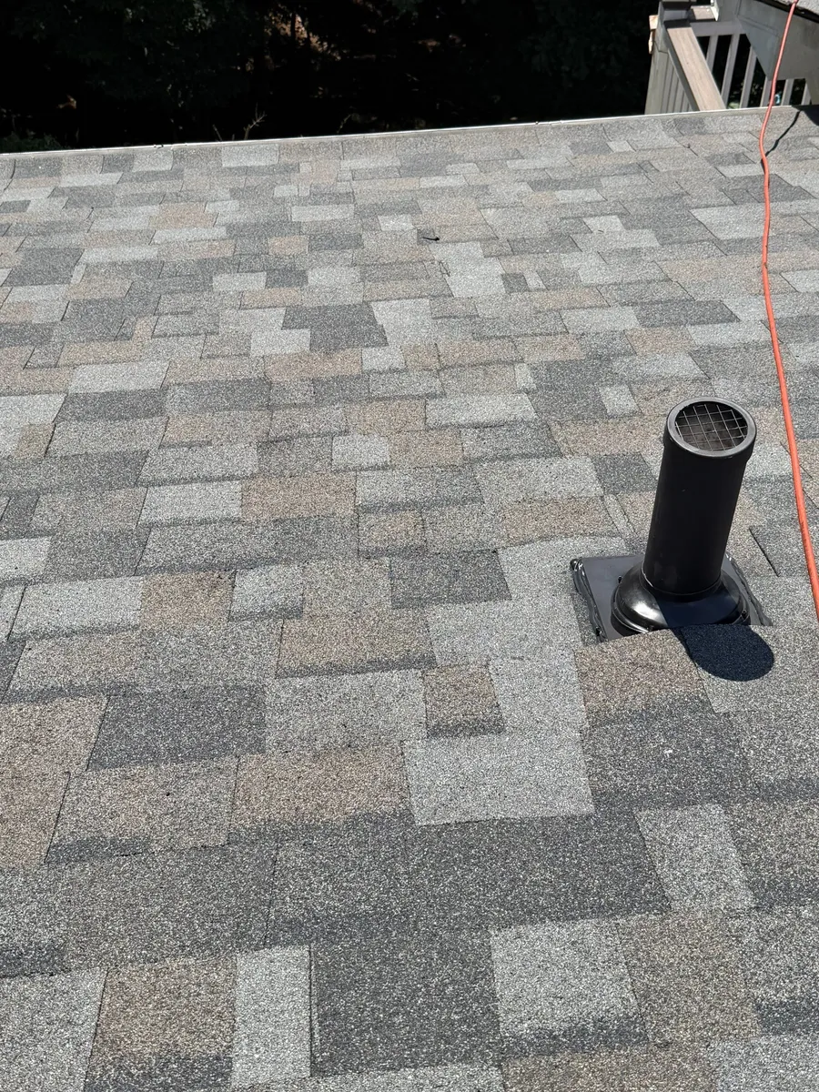 Roof vent set into the shingle field partway up the slope, ridge running across above it