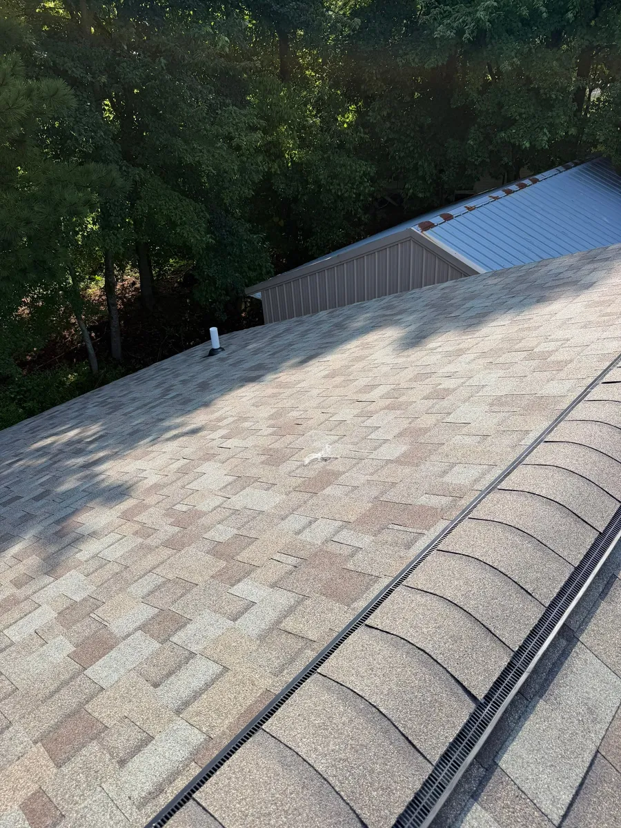 Finished shingle field with a ridge vent at the peak and a plumbing vent partway down the slope