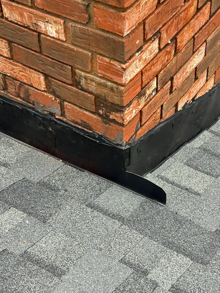 Corner of a brick chimney showing step flashing and counter-flashing tucked into the mortar joint