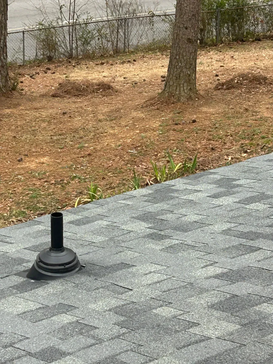 Single pipe boot bedded into fresh architectural shingles, viewed close