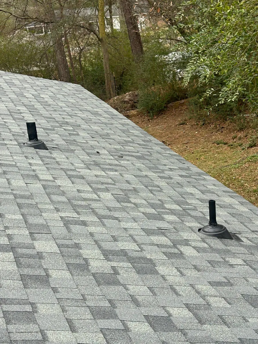 New grey shingles with black pipe boots seated flat against the slope