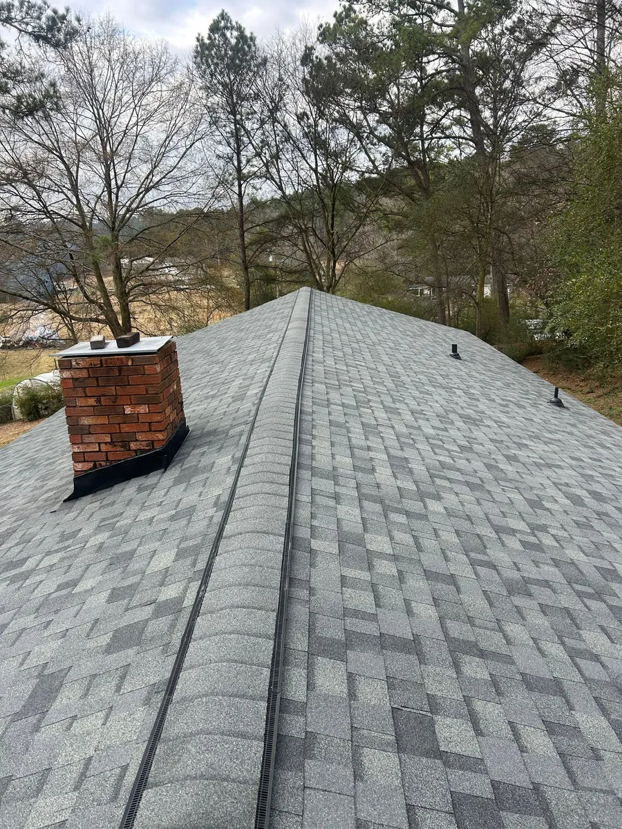 Finished grey shingle roof running to the ridge, brick chimney at the left gable